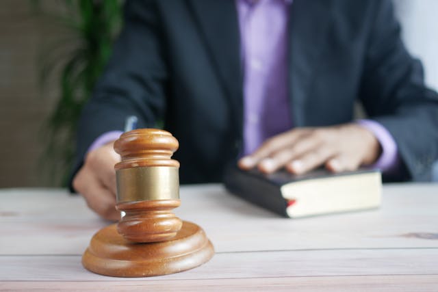 judge hitting gavel with hand on book