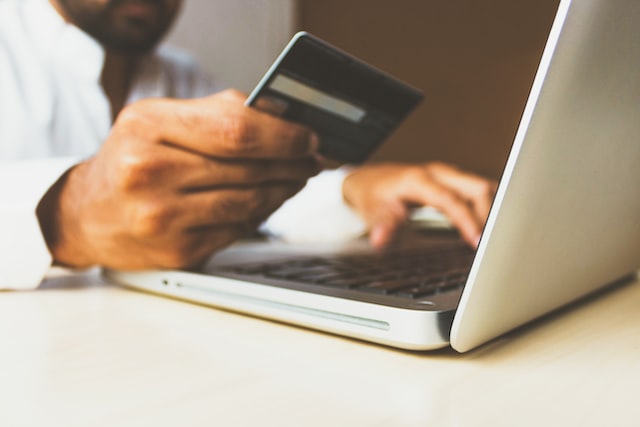 person holding credit card near computer