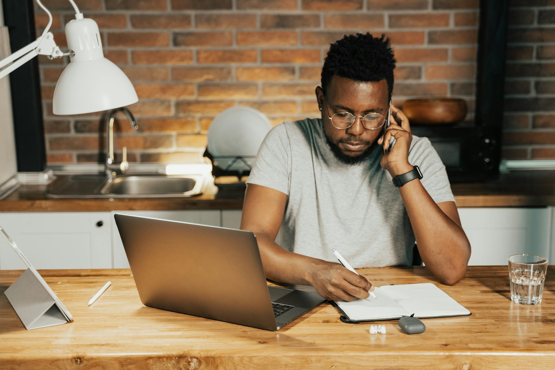 man on phone while writing on paper